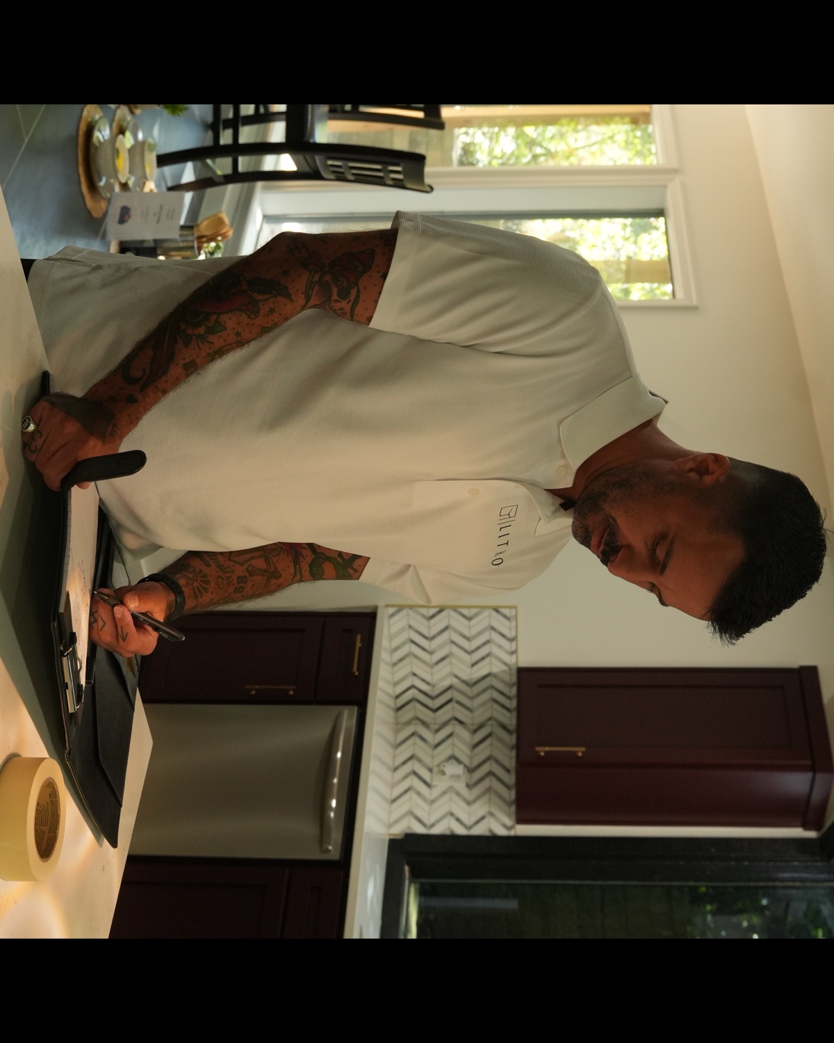 Steven Benike, owner of Lithos, reviewing paperwork at a client's kitchen island in Jenks