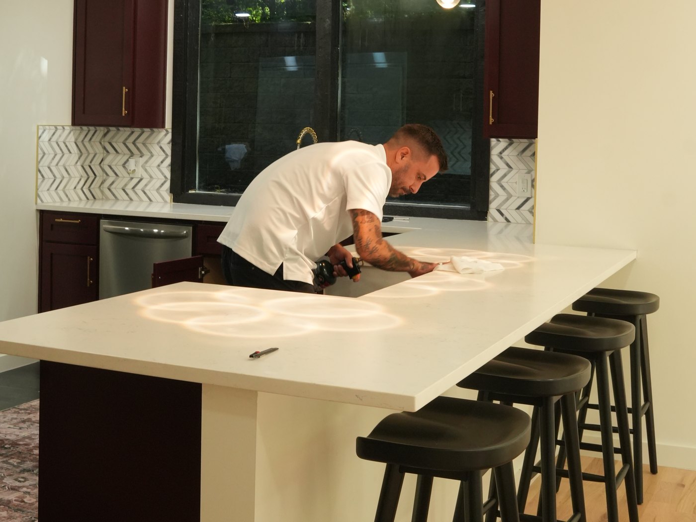 Installer squeegeeing film across a quartz island